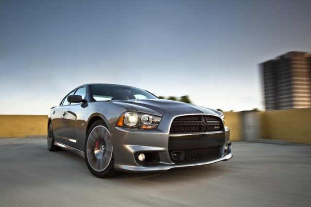 Silver Dodge Charger driving through a city at dusk