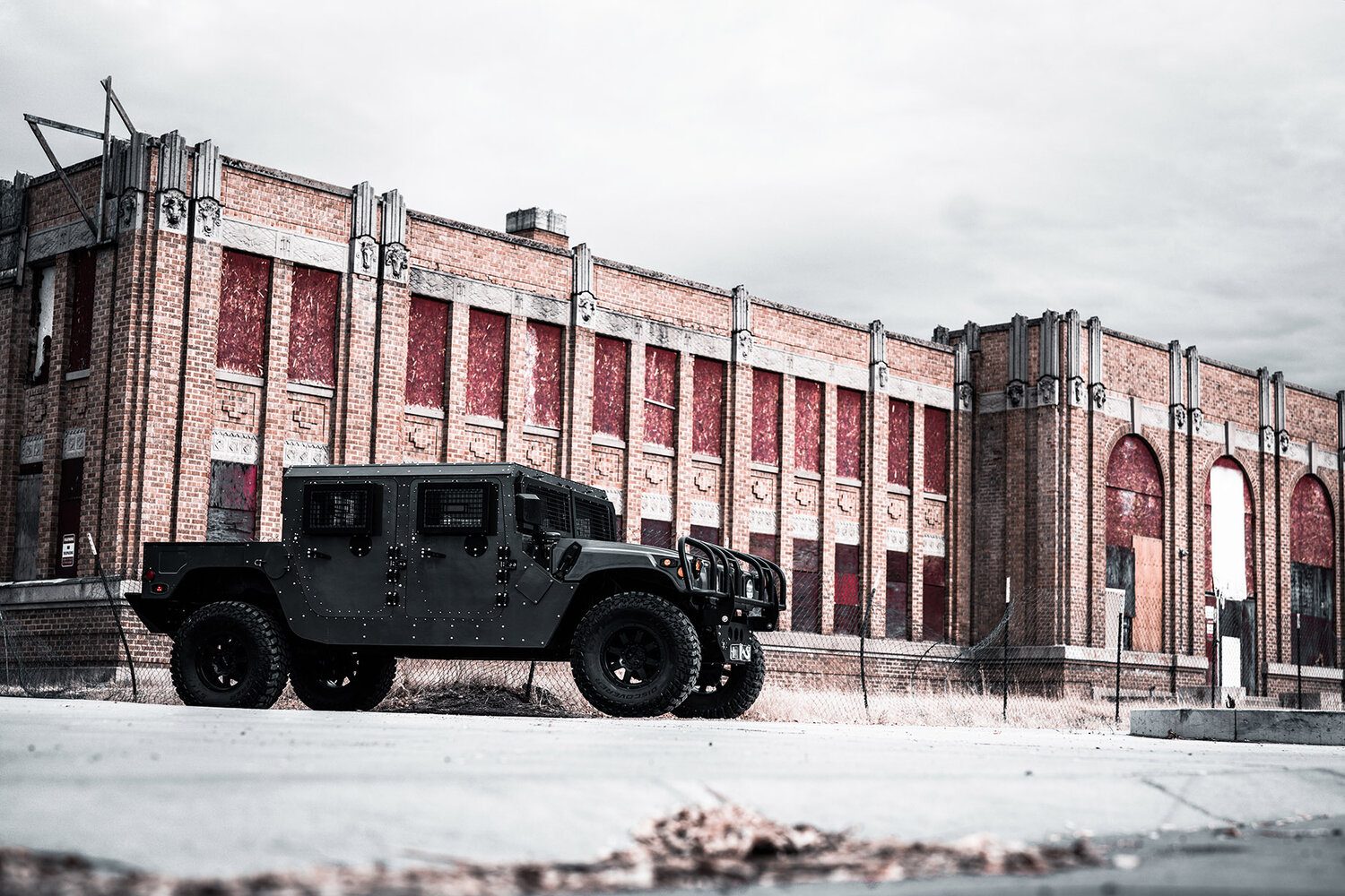 Blacked-out ruggedized HMMWV parked outside an industrial building
